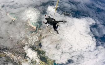 Skydivers descending over Shellharbour, Sydney, with coastal view from 15,000 feet.