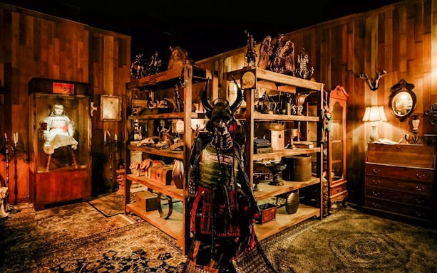 Haunted artifacts room with samurai armor and doll display, part of The Conjuring Universe Tour in Thailand.