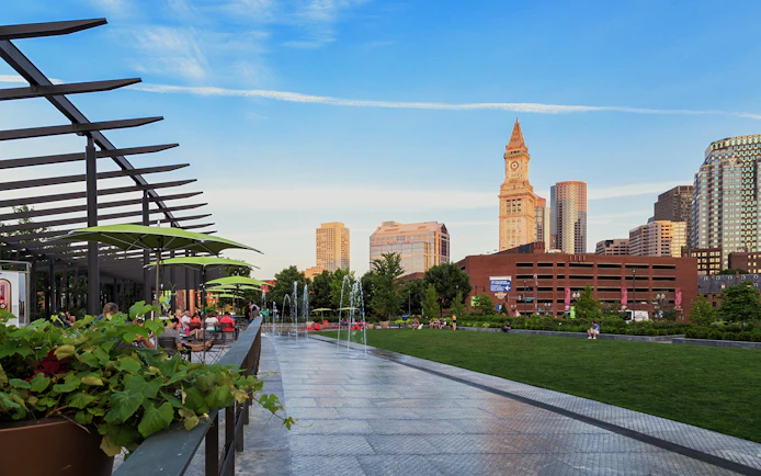 Rose Kennedy Greenway Park in Boston with people relaxing and city skyline in the background.