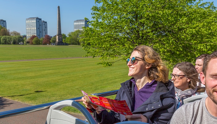 Open-top bus tour passing Kelvingrove Art Gallery in Glasgow.