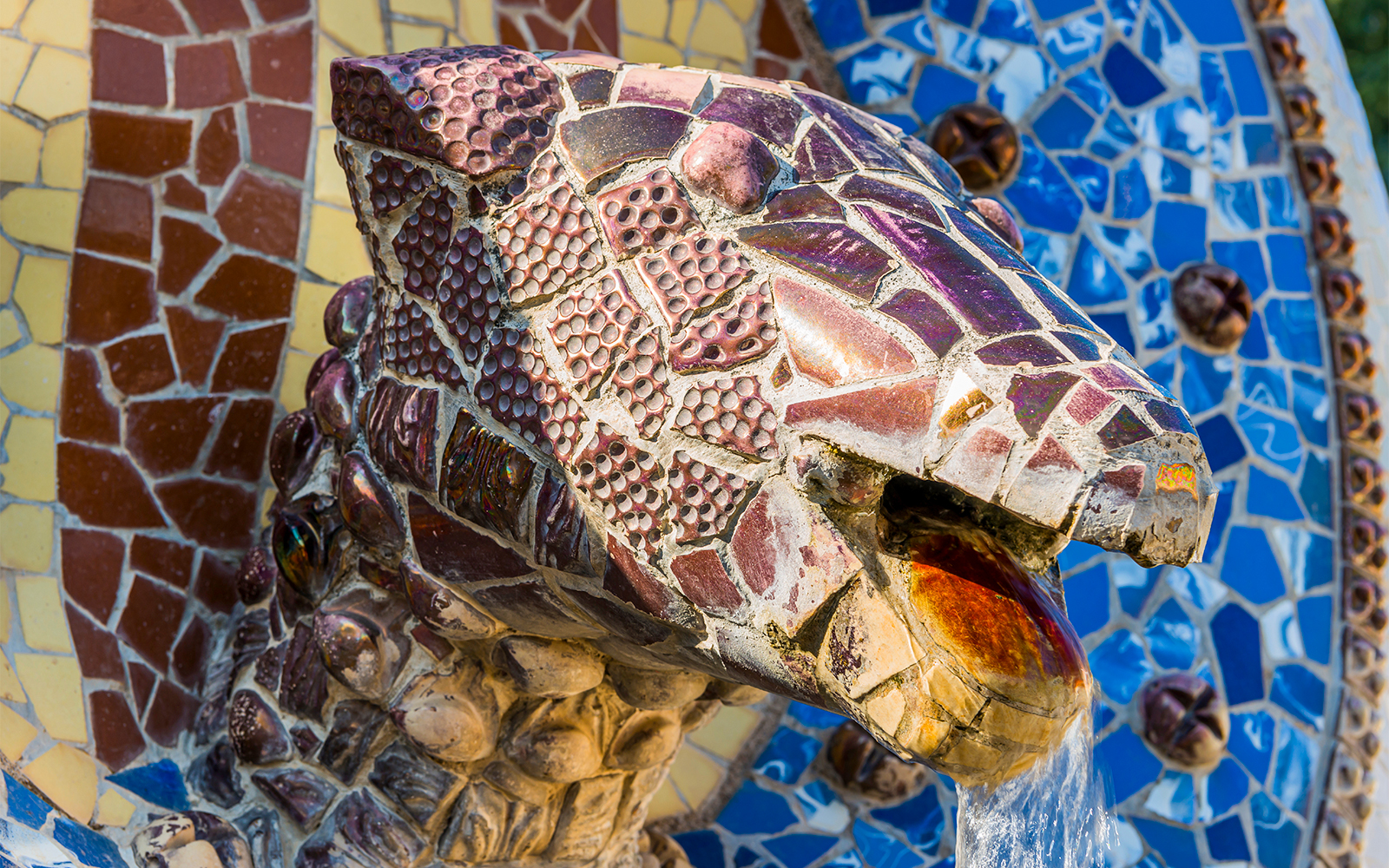 Mosaic dragon head sculpture at Park Güell, Barcelona, with water flowing from its mouth.
