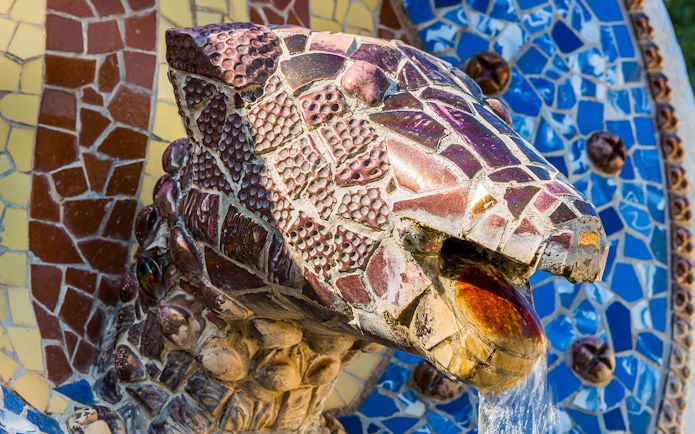 Mosaic dragon head sculpture at Park Güell, Barcelona, with water flowing from its mouth.
