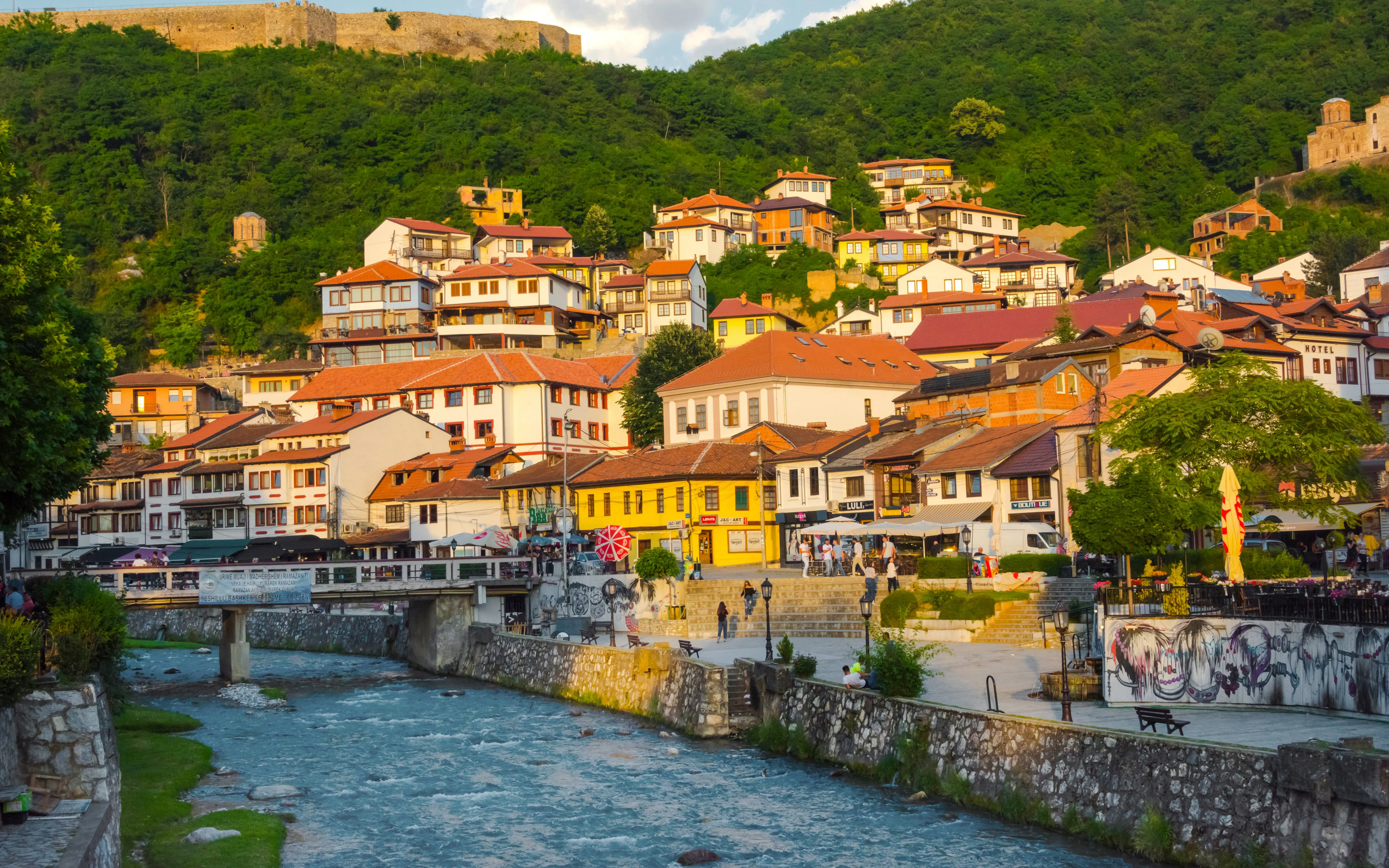 Houses along the river in the old town of Prizren, Kosovo, with a hillside backdrop.
