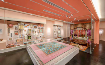 Peranakan Museum gallery with traditional textiles and ornate wooden bed display.