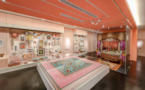 Peranakan Museum gallery with traditional textiles and ornate wooden bed display.