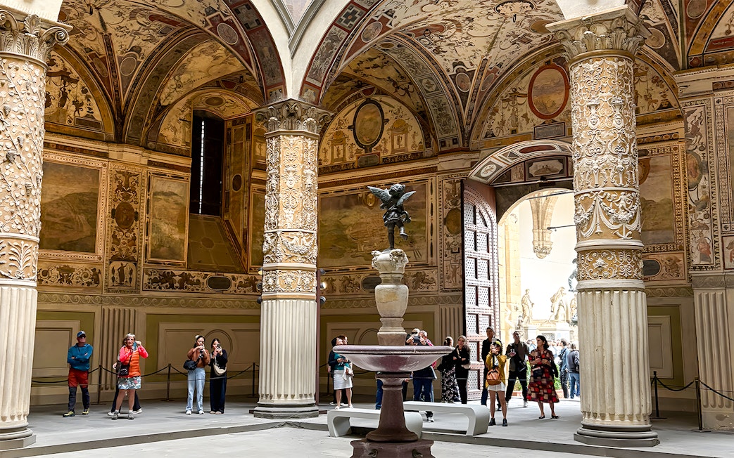 Tourists exploring the ornate courtyard of Palazzo Vecchio in Florence.