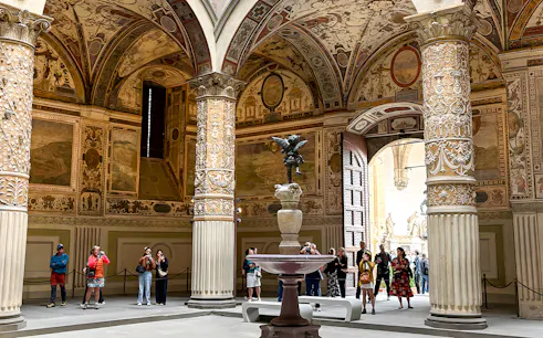 Tourists exploring the ornate courtyard of Palazzo Vecchio in Florence.