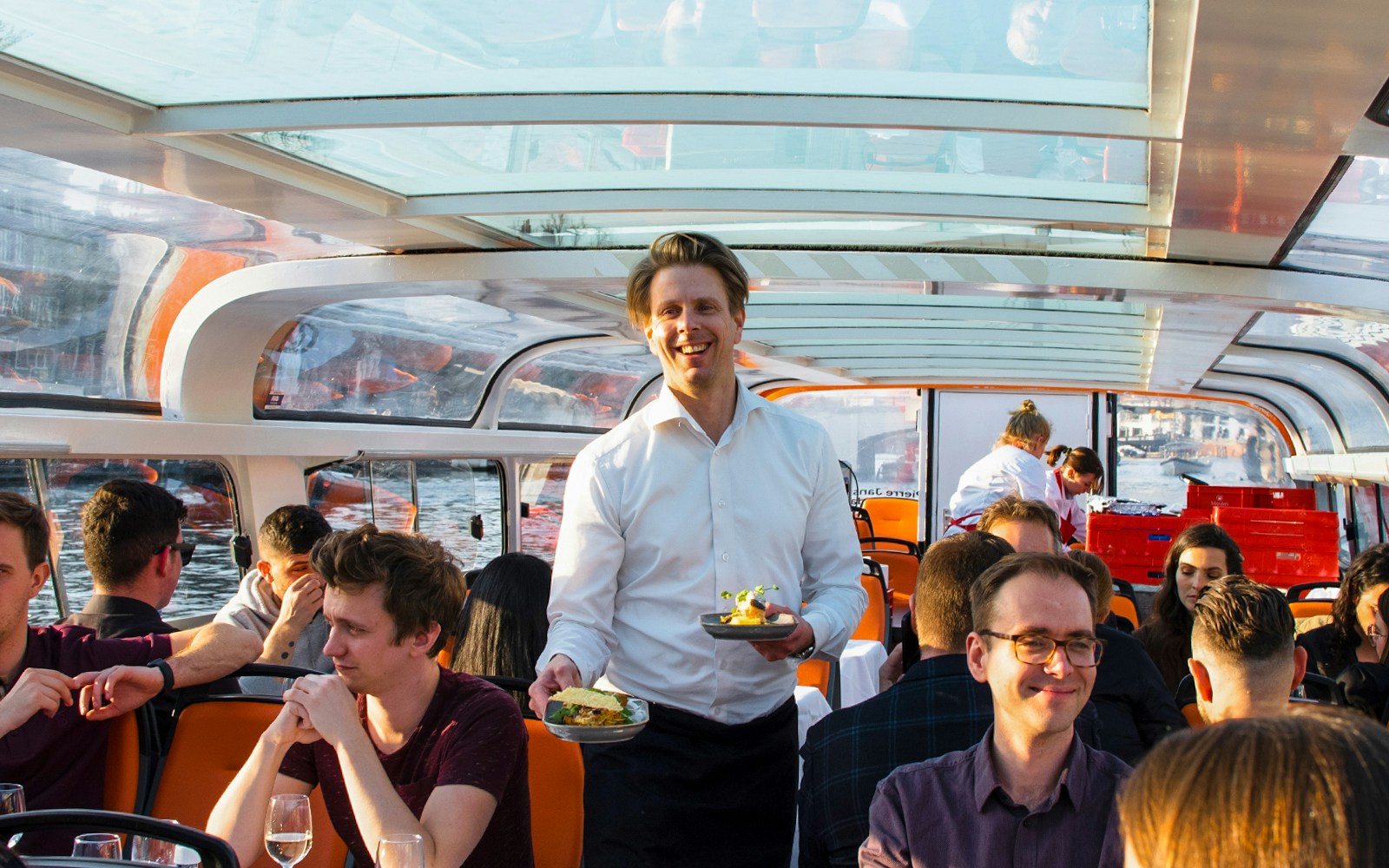 Service staff serving dinner on an Amsterdam canal cruise.