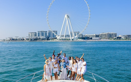 Group enjoying Dubai Luxury Yacht Tour with Ain Dubai in the background.