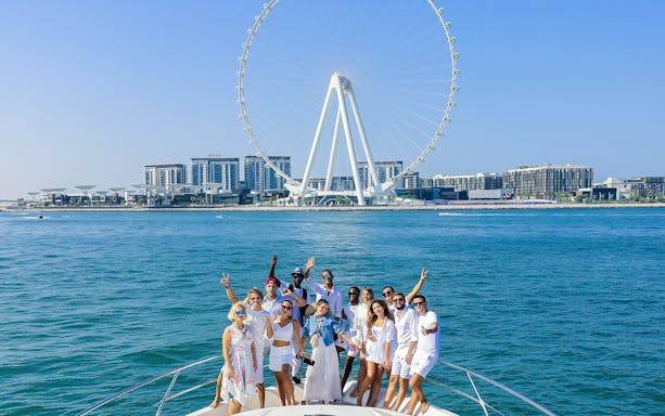 Group enjoying Dubai Luxury Yacht Tour with Ain Dubai in the background.