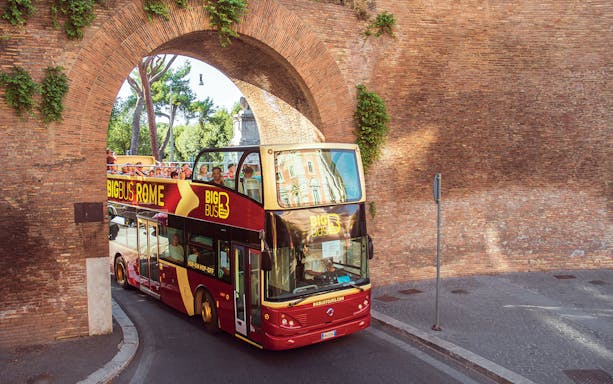 Open-top bus passing through ancient Roman archway on Big Bus Tours Rome.