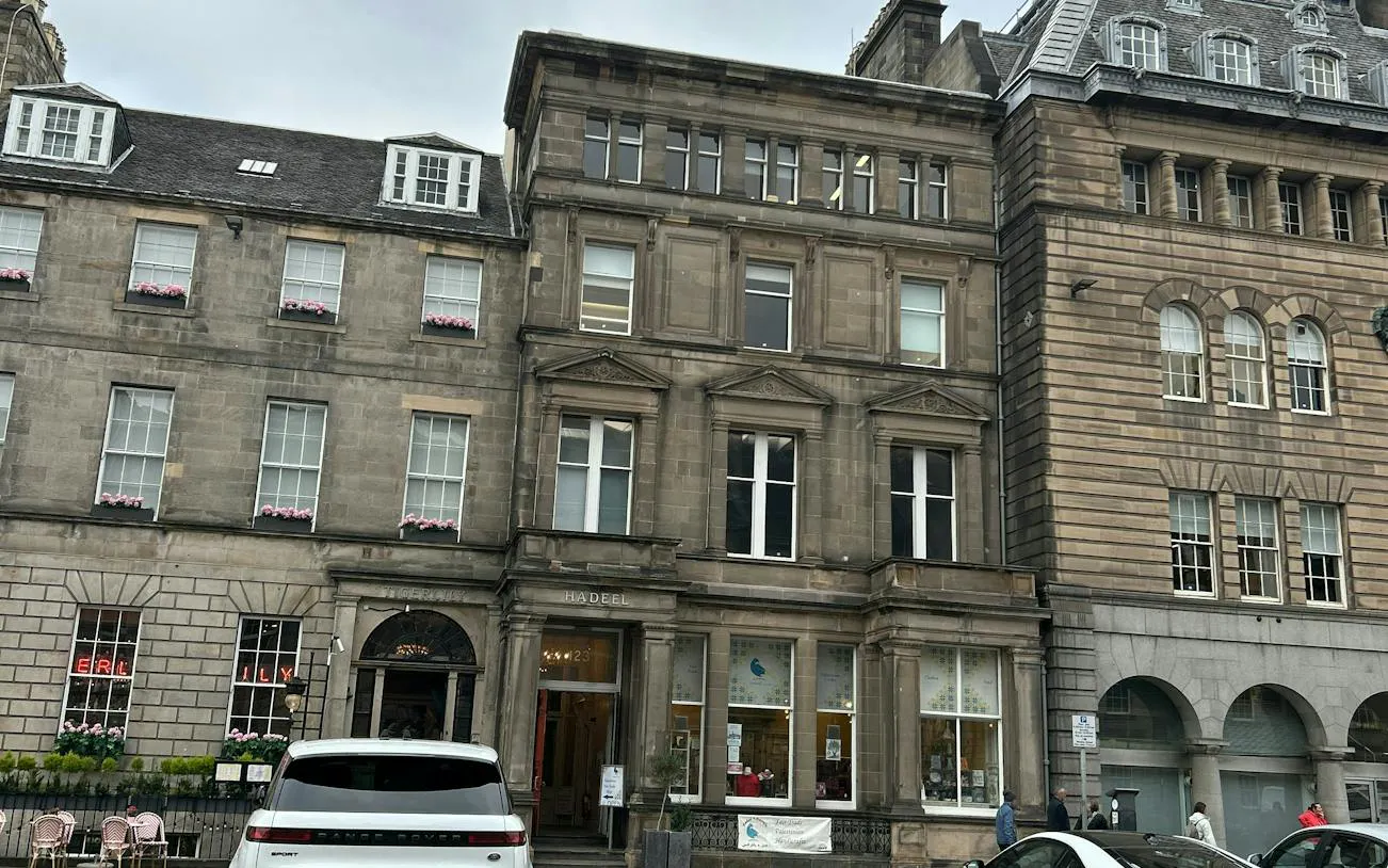 Historic stone buildings on a street in Edinburgh, part of the Secret Society Detective Mystery game.