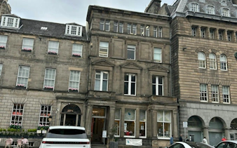 Historic stone buildings on a street in Edinburgh, part of the Secret Society Detective Mystery game.