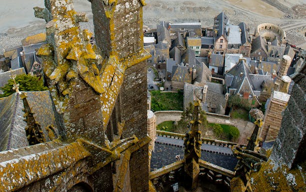 View from Mont Saint Michel Abbey overlooking village rooftops and stone architecture.