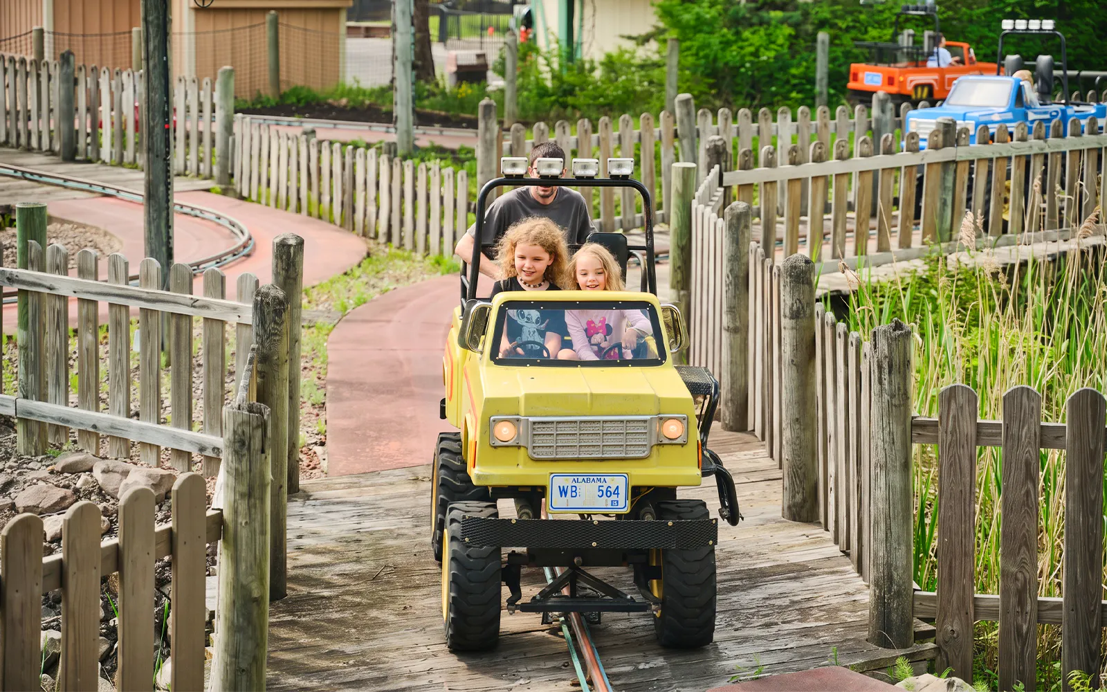 Children driving a yellow jeep on the Tree Stump Turnpike ride at Six Flags Darien Lake.