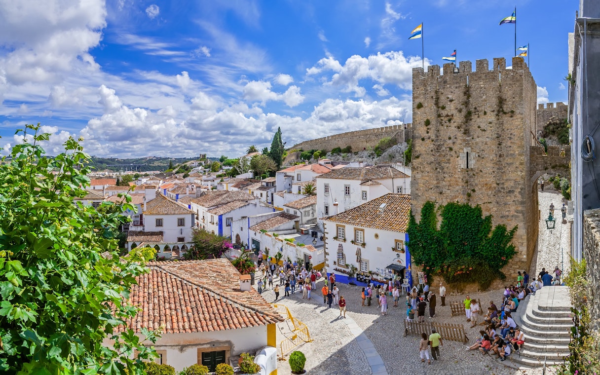Obidos medieval town with castle walls, cobblestone streets, and tourists exploring.