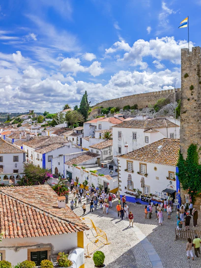 Obidos medieval town with castle walls, cobblestone streets, and tourists exploring.