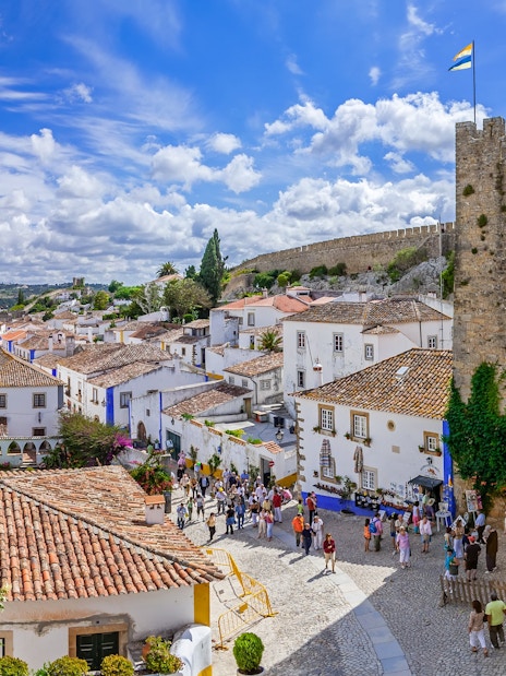 Obidos medieval town with castle walls, cobblestone streets, and tourists exploring.