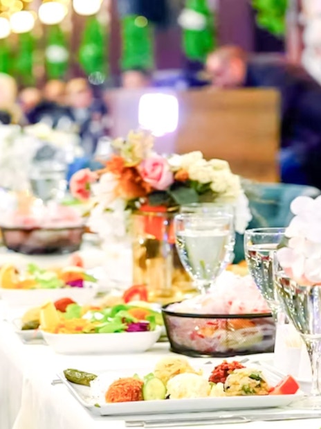 Turkish dinner setup on Bosphorus night cruise with floral centerpieces and traditional dishes.