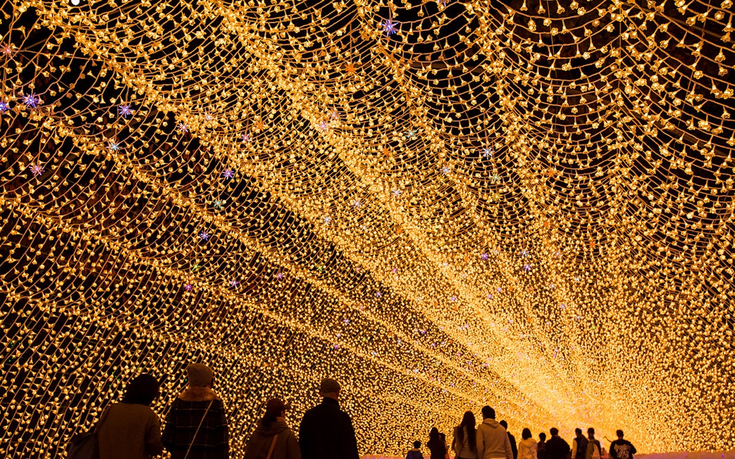 Tunnel of golden lights at Nabana no Sato, Japan, viewed by visitors, accessible with Kintetsu Rail Pass.