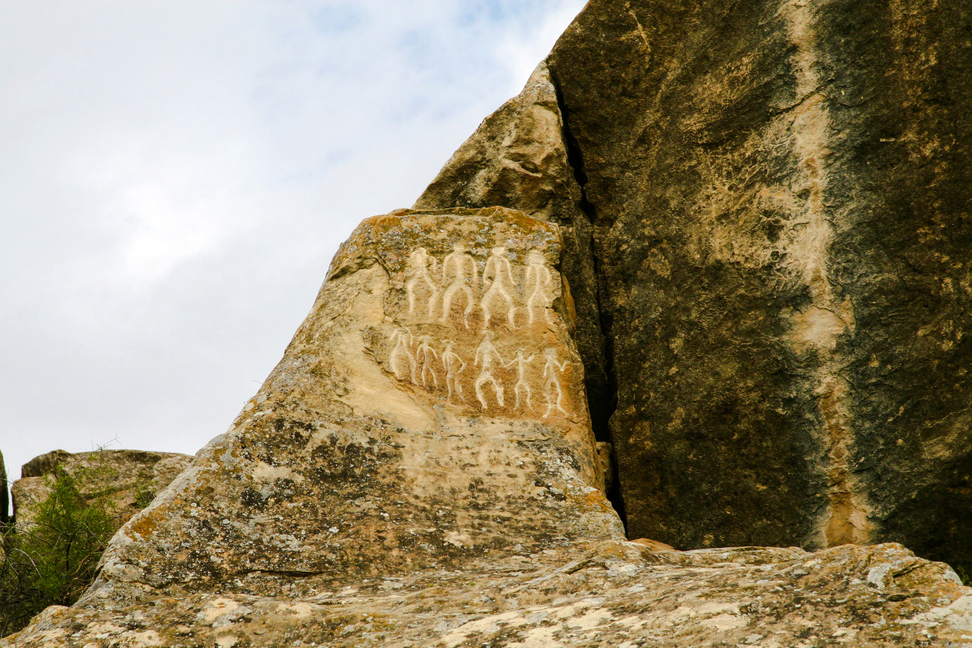 Petroglyphs on rock surface at Gobustan, Baku, depicting ancient human figures.