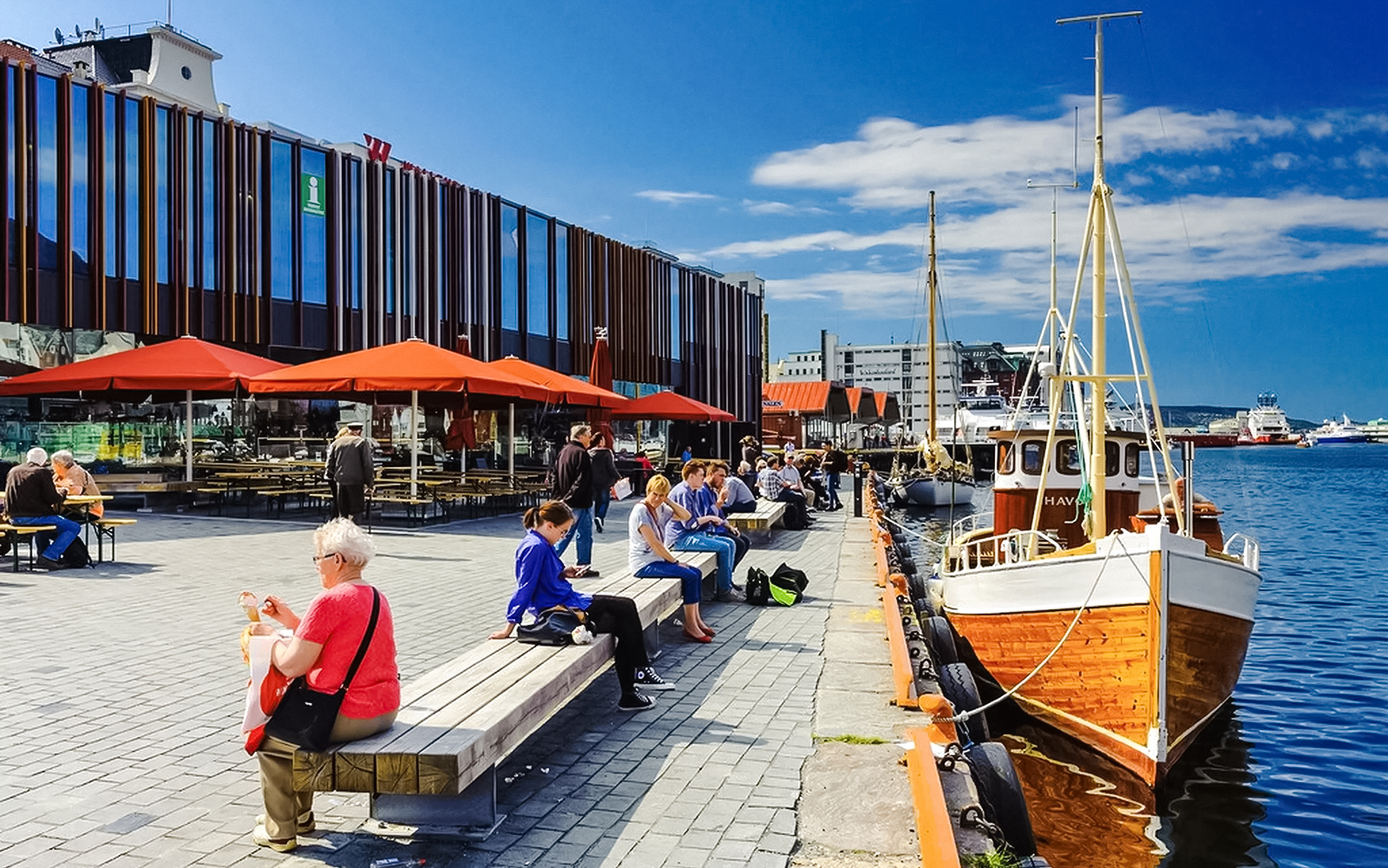 Bergen Fish Market waterfront with people sitting and boats docked nearby.