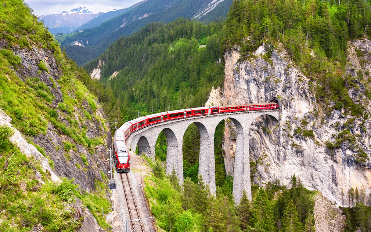 Bernina Train crossing a stone viaduct in the Swiss Alps.