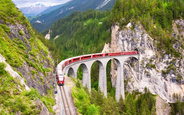 Bernina Train crossing a stone viaduct in the Swiss Alps.