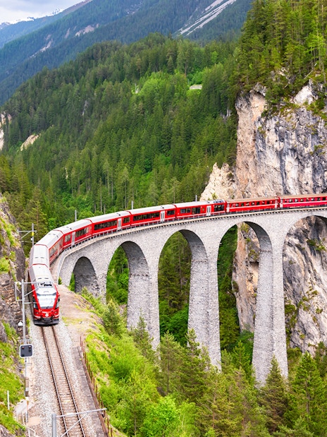 Bernina Train crossing a stone viaduct in the Swiss Alps.