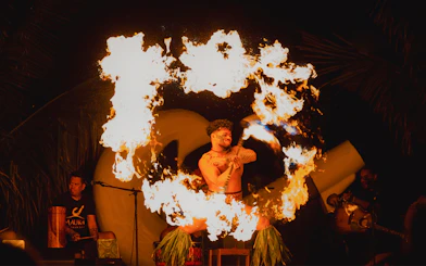 Fire dancer performing at Mauka Warriors Luau with flames swirling around.