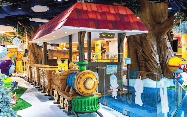 Pororo Park Singapore indoor train ride with colorful characters and tree-themed decor.