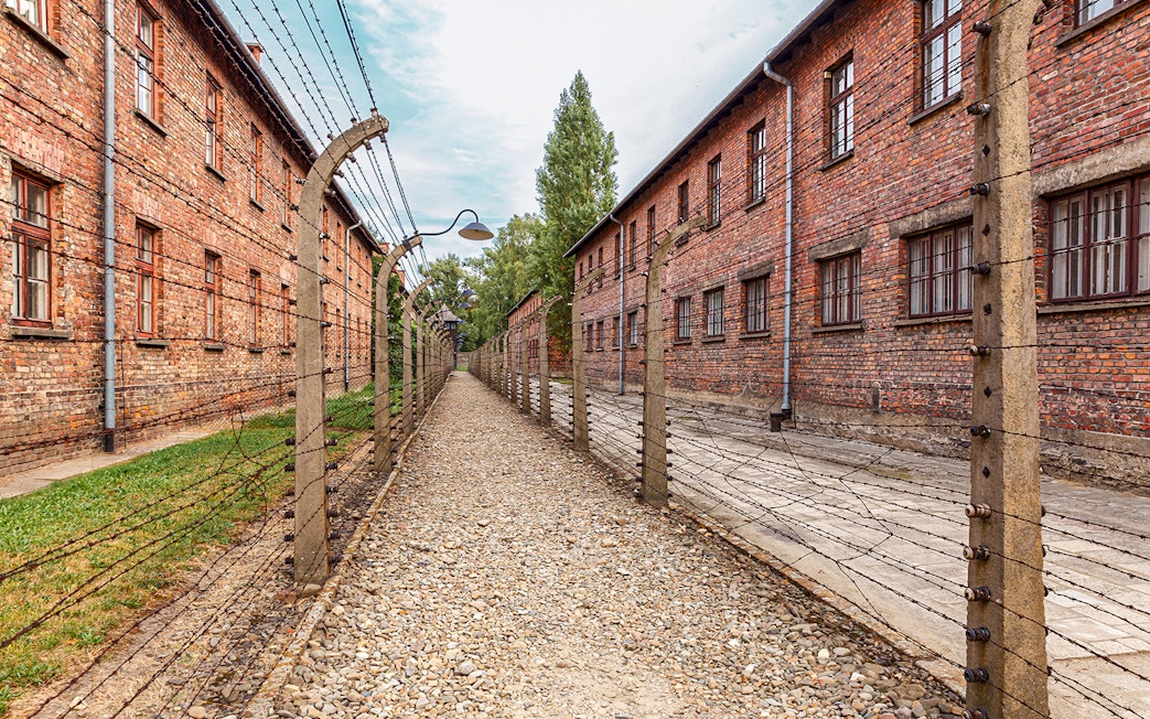 Exterior view of Auschwitz I barracks with barbed wire fences, Poland.