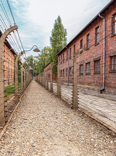 Exterior view of Auschwitz I barracks with barbed wire fences, Poland.