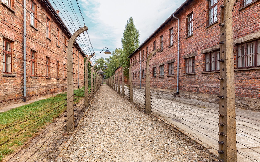 Exterior view of Auschwitz I barracks with barbed wire fences, Poland.