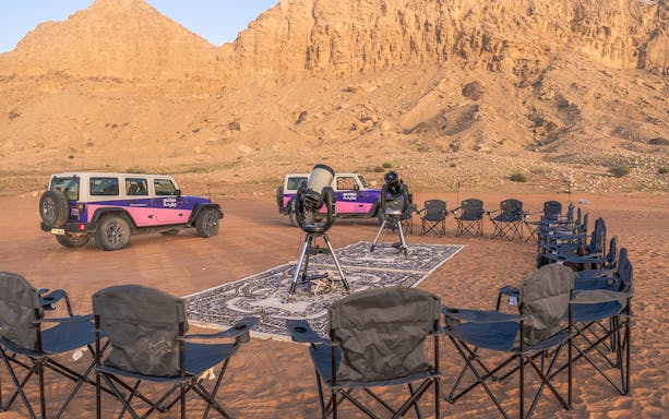 Stargazing setup with telescopes and chairs in Mleiha desert.