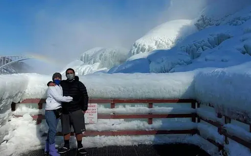 Couple standing on a snowy observation deck at Niagara Falls during winter, USA.