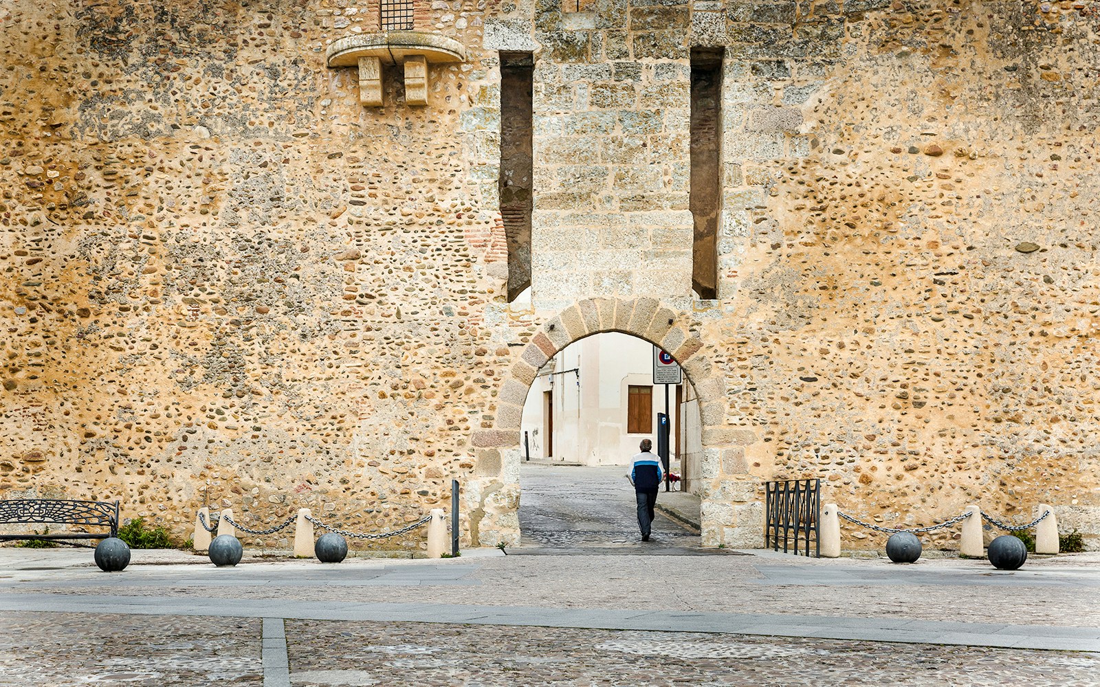 Stone archway entrance at Castelo Rodrigo, Douro Valley, with a person walking through.