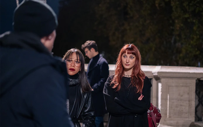 Tour group listening to a guide during a haunted ghosts tour in Rome at night.