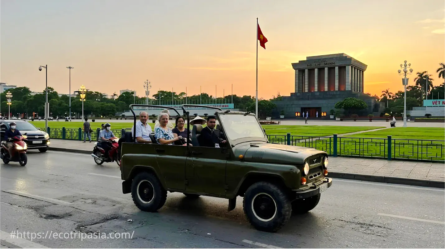 Jeep tour with Ao Dai guides passing Ho Chi Minh Mausoleum, Hanoi at sunset.