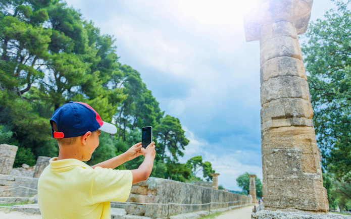 Young traveler photographing ancient ruins at Olympia, Greece, near Katakolo Port.