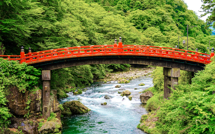 Shinkyo Bridge over Daiya River surrounded by lush greenery, Nikko Toshogu Shrine, Japan.