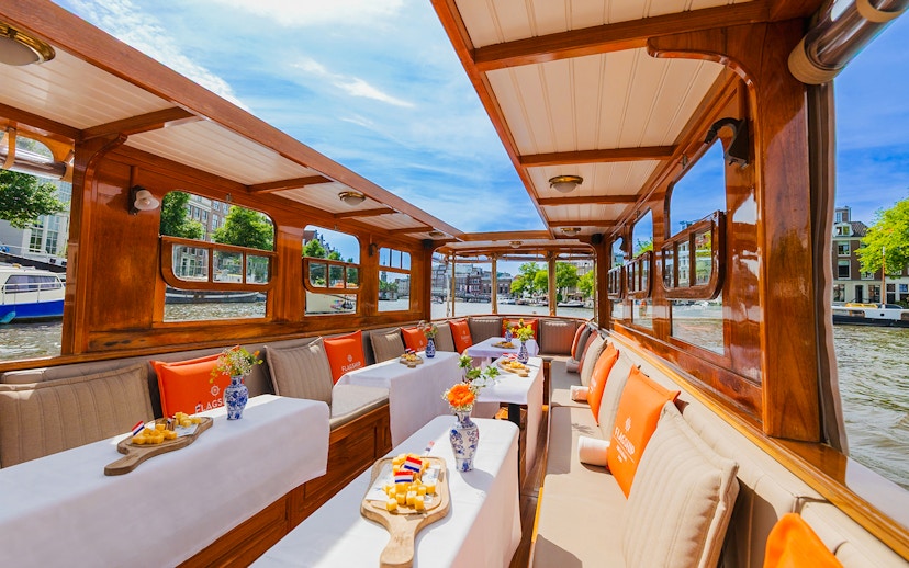 Interiors of a canal cruise boat in Amsterdam with tables set for dining.