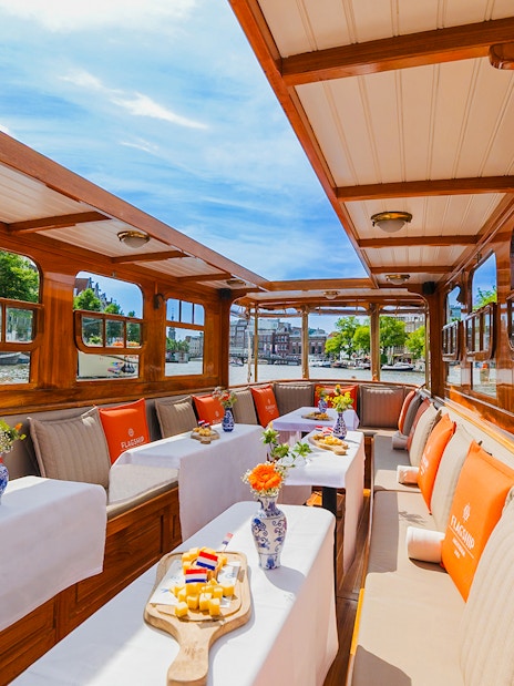 Interiors of a canal cruise boat in Amsterdam with tables set for dining.