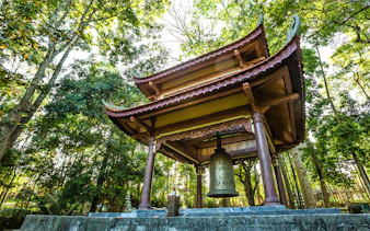 Tu Hieu Pagoda bell pavilion surrounded by lush trees in Hue, Vietnam.