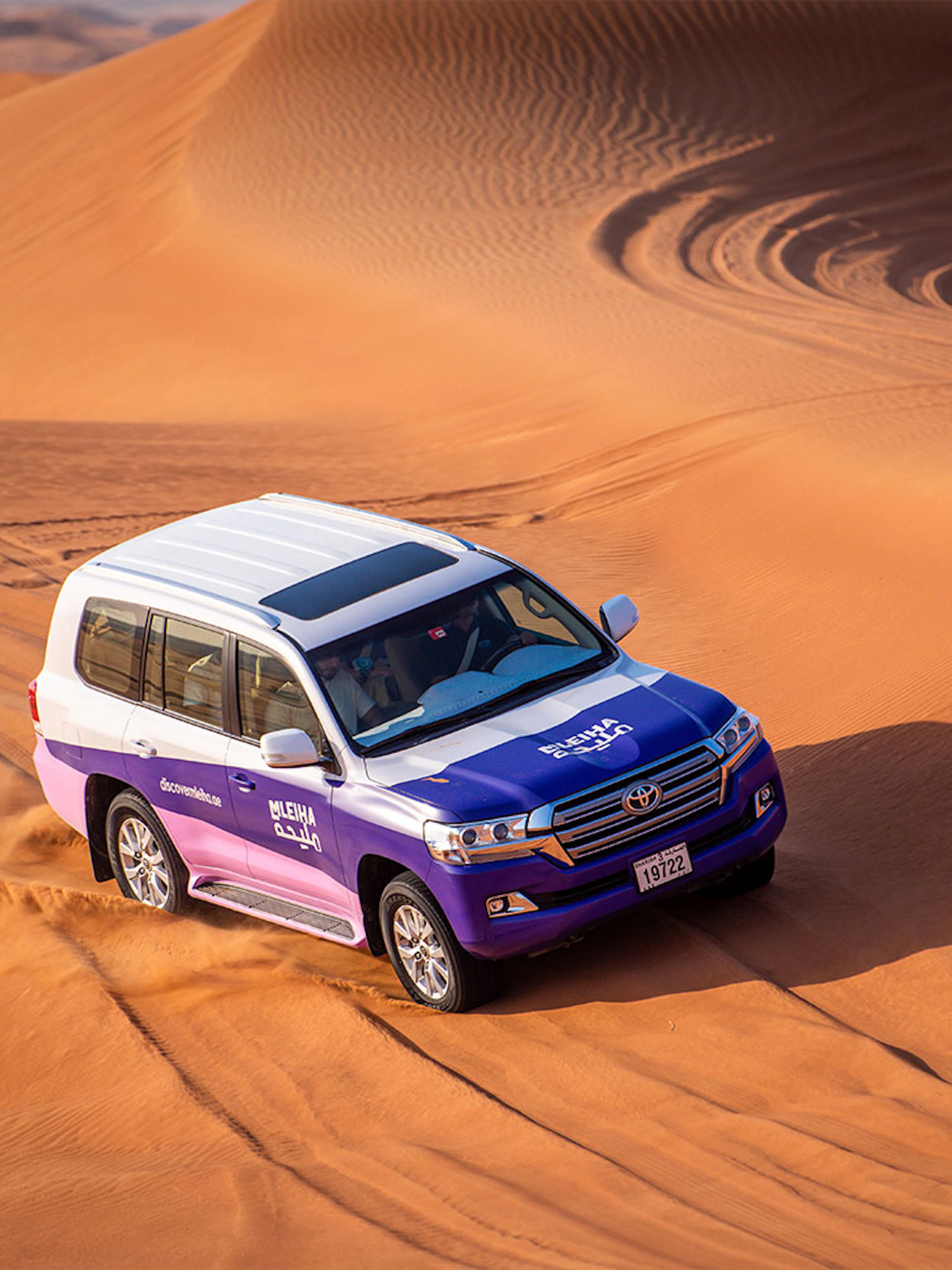 SUV driving through sand dunes on Mleiha tour with Fossil Rock visit.