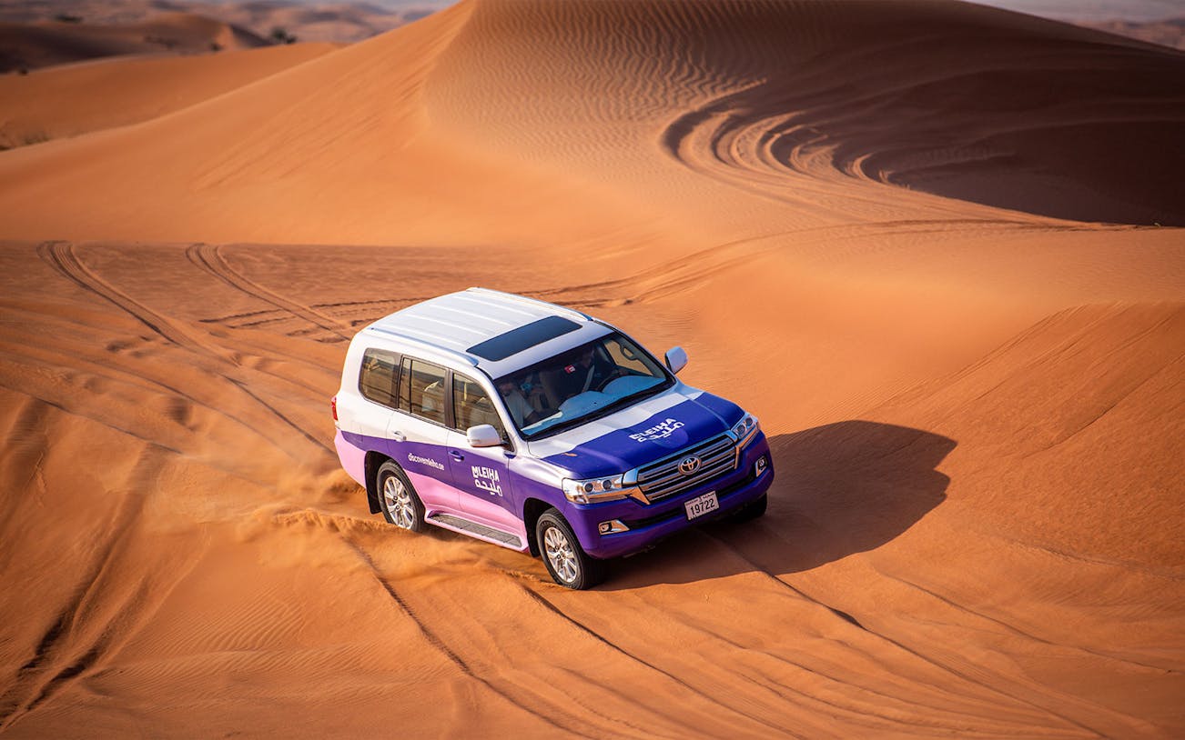 SUV driving through sand dunes on Mleiha tour with Fossil Rock visit.