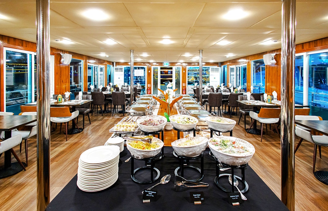Dining setup on Alexandra Sea Lounge Dhow Cruise with buffet and seating area.