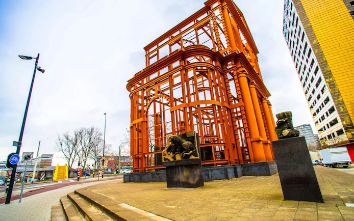 Orange steel structure with lion statues in Rotterdam, part of the Spy Hunt city exploration game.
