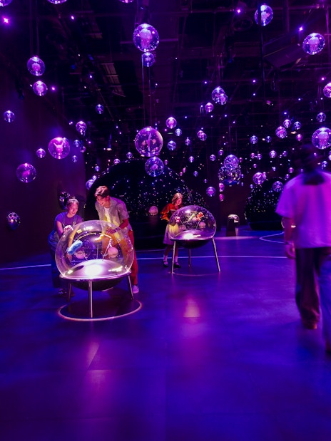 Interactive orb exhibit at Exploria, Mandai Wildlife, with visitors engaging in a vibrant, illuminated space.