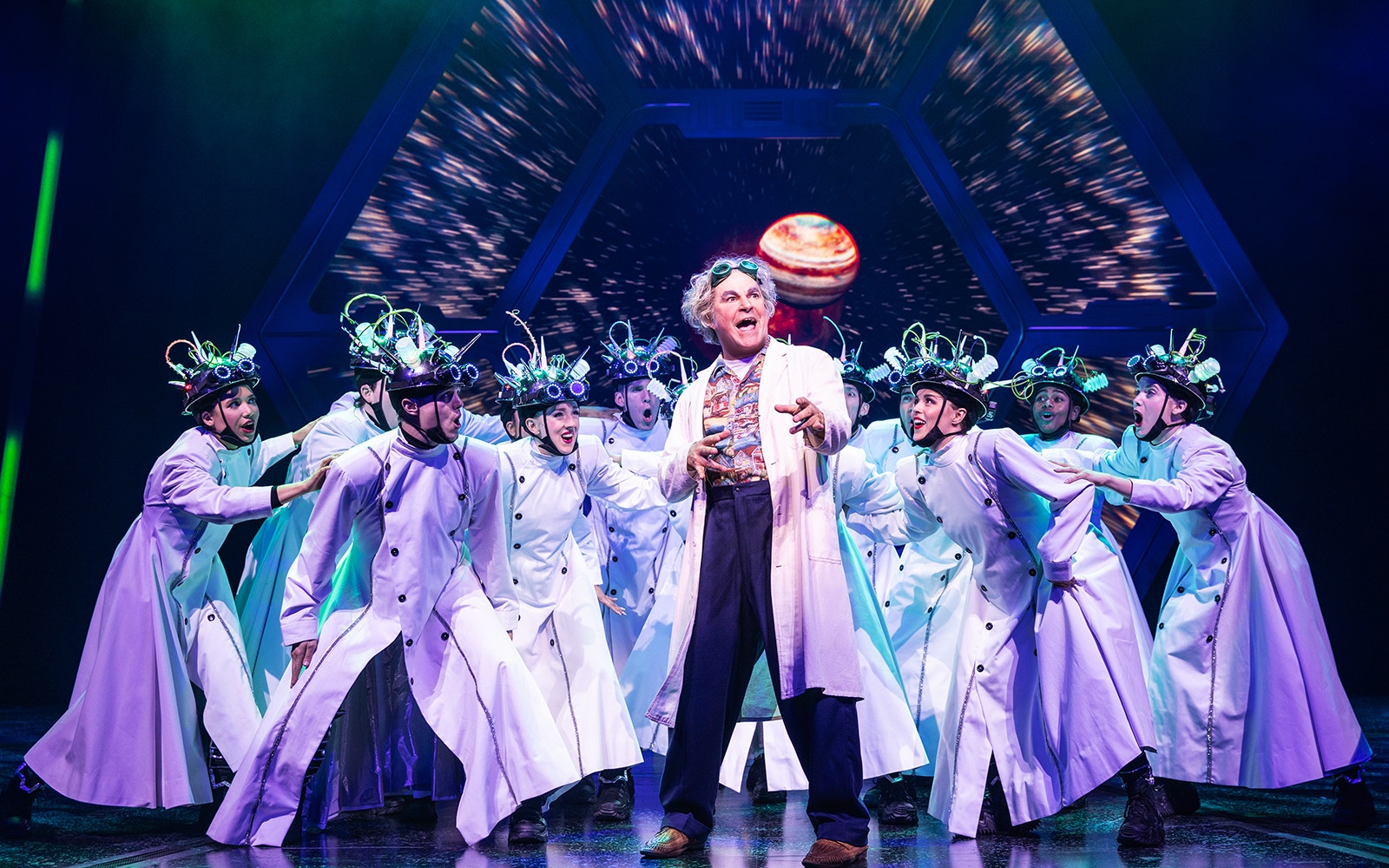 Cast performing a scene from Back to the Future the Musical with futuristic costumes.